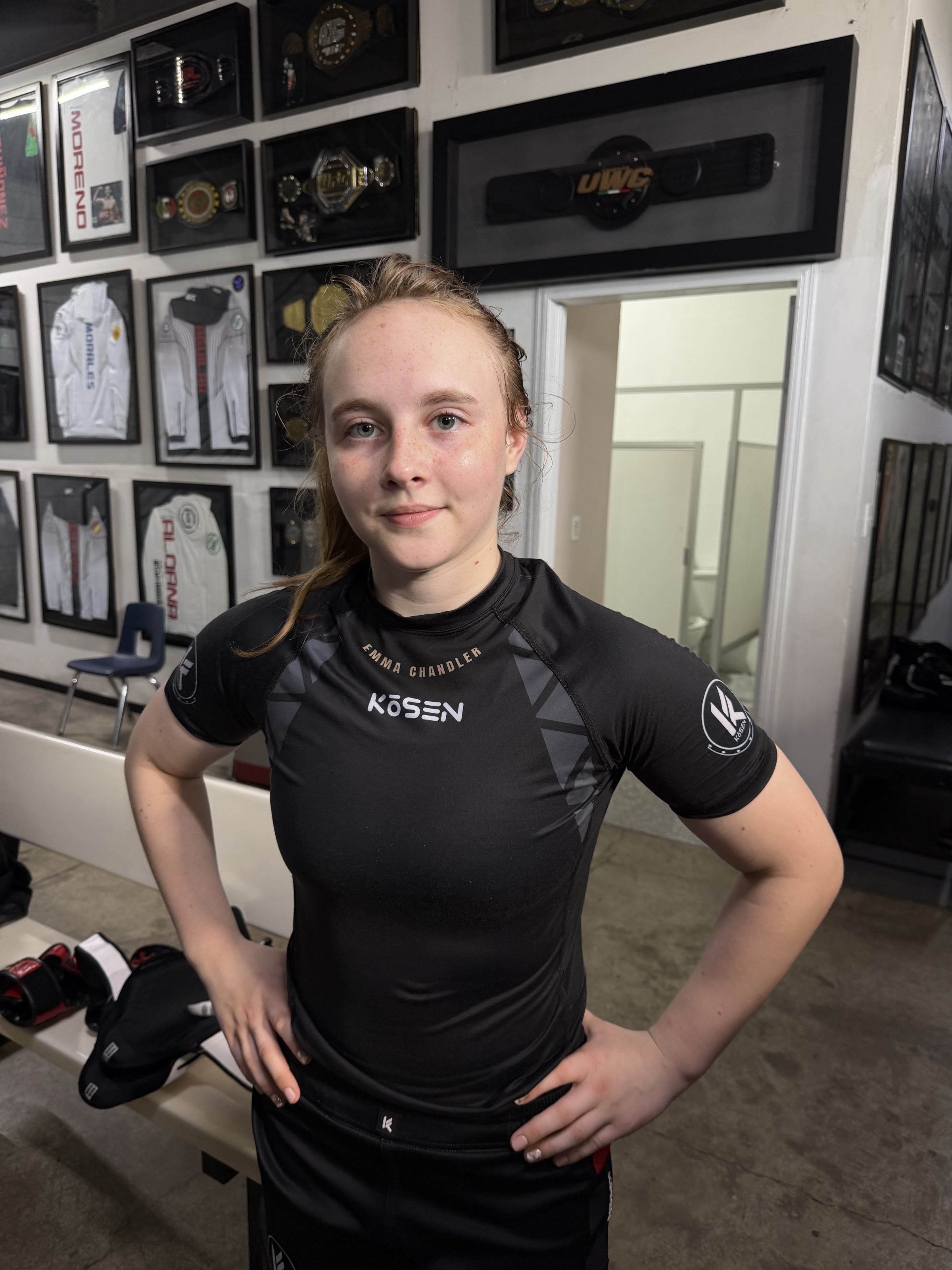 Emma Chandler at the championship wall — belts and medals documented behind her